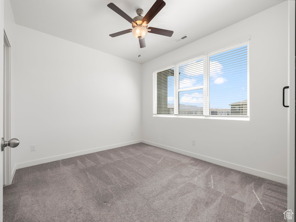 Carpeted empty room with baseboards and ceiling fan