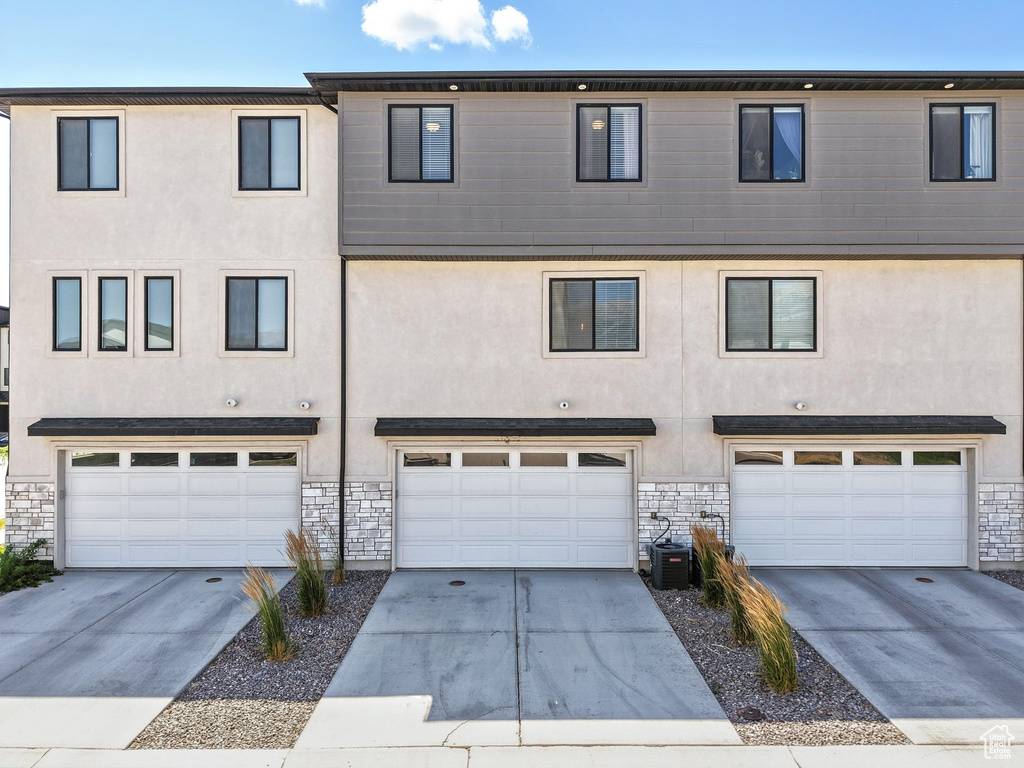 View of front of home featuring stucco siding, a garage, and stone siding