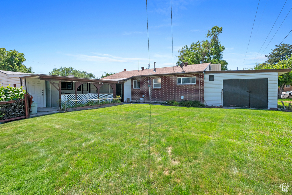 Back of house with a yard and brick siding