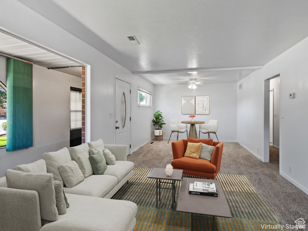 Carpeted living area with ceiling fan and baseboards