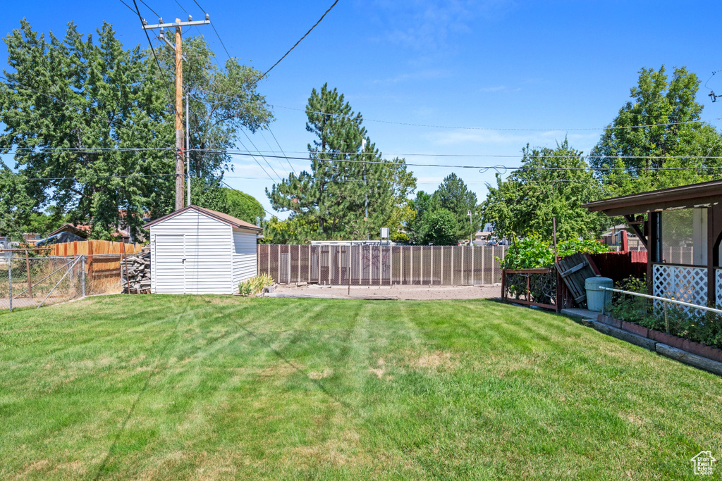 Fenced backyard featuring a storage unit