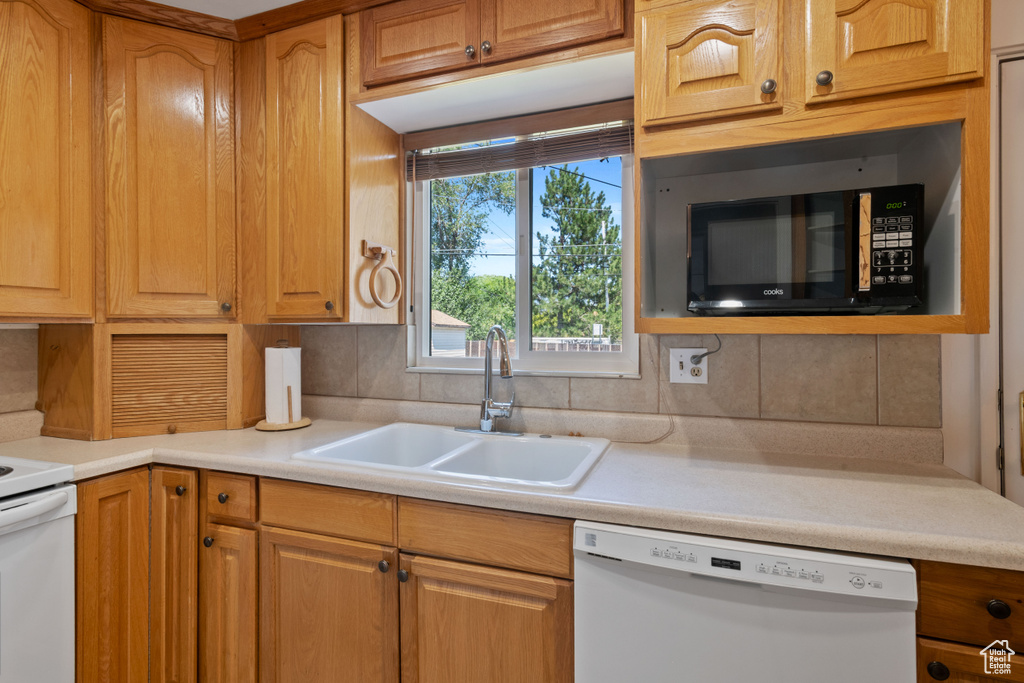 Kitchen featuring dishwasher, black microwave, light countertops, and tasteful backsplash
