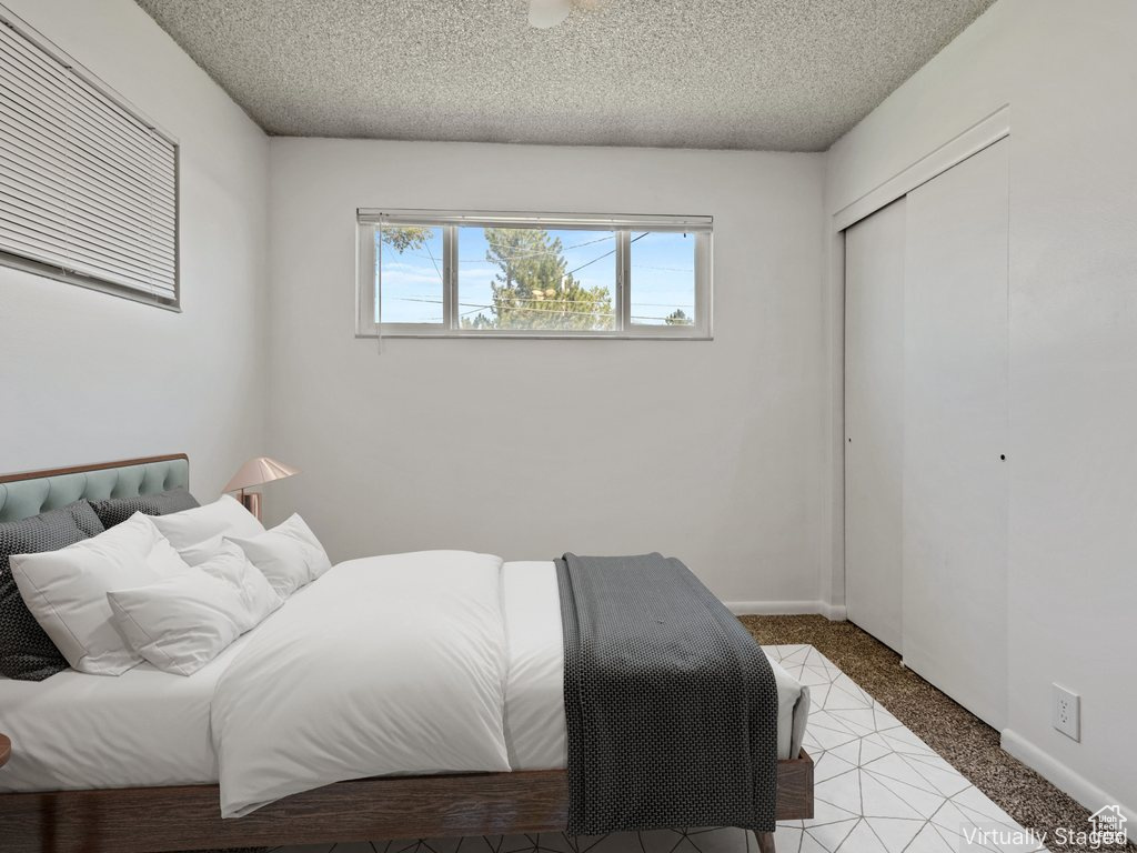 Carpeted bedroom with a textured ceiling and a closet