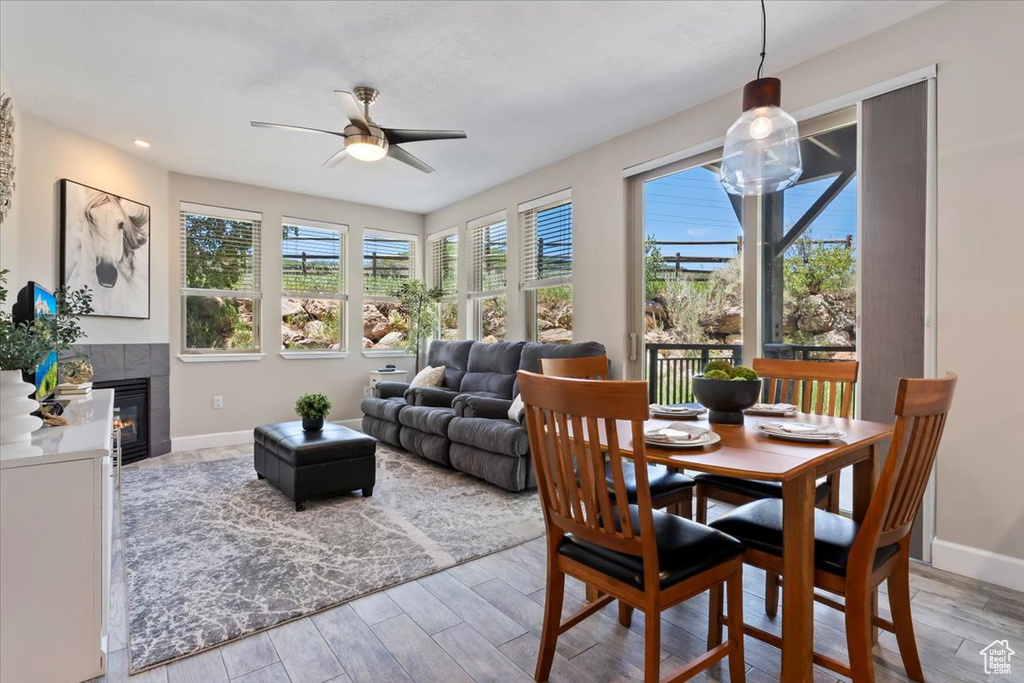 Dining room featuring light wood-style floors, ceiling fan, a tiled fireplace, and recessed lighting