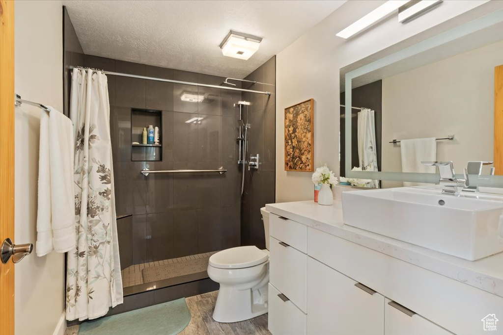 Full bath featuring vanity, a shower stall, and wood finished floors