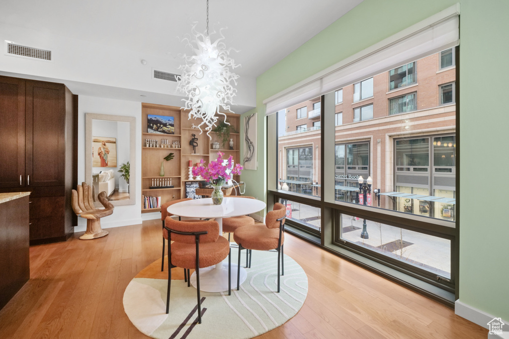 Dining room with light wood finished floors, a chandelier, and built in shelves