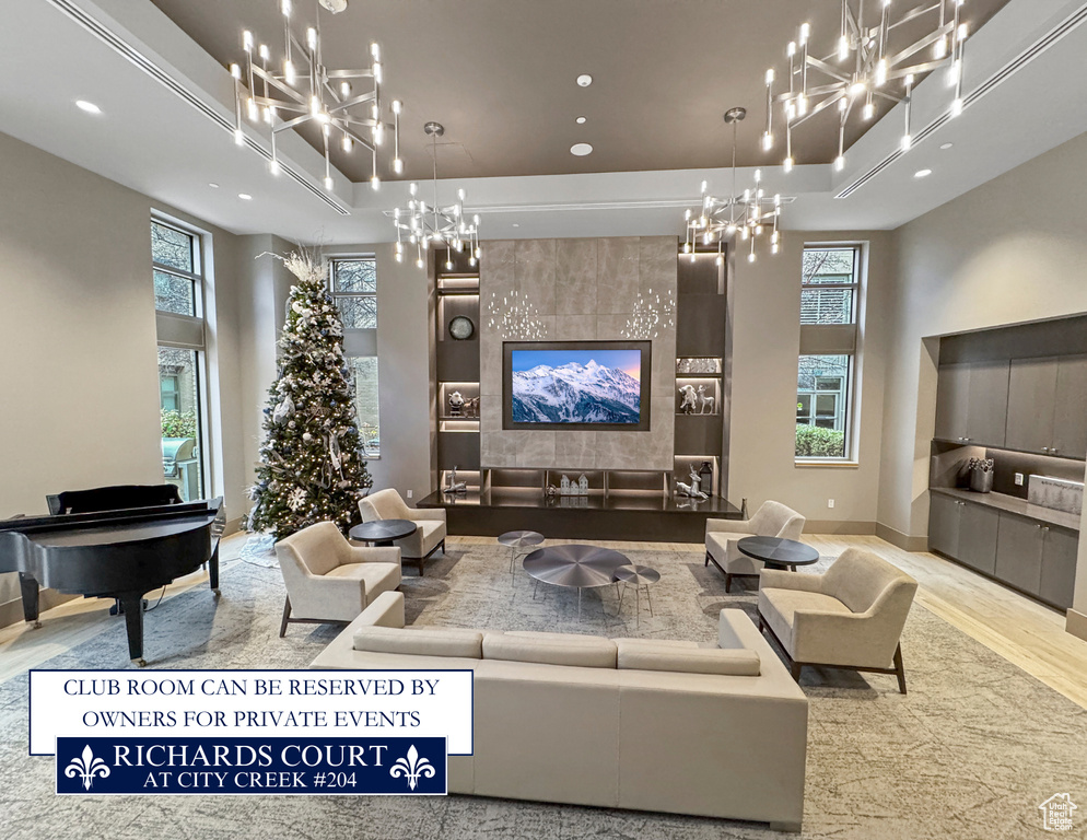 Living area featuring a chandelier, wood finished floors, plenty of natural light, a towering ceiling, and recessed lighting