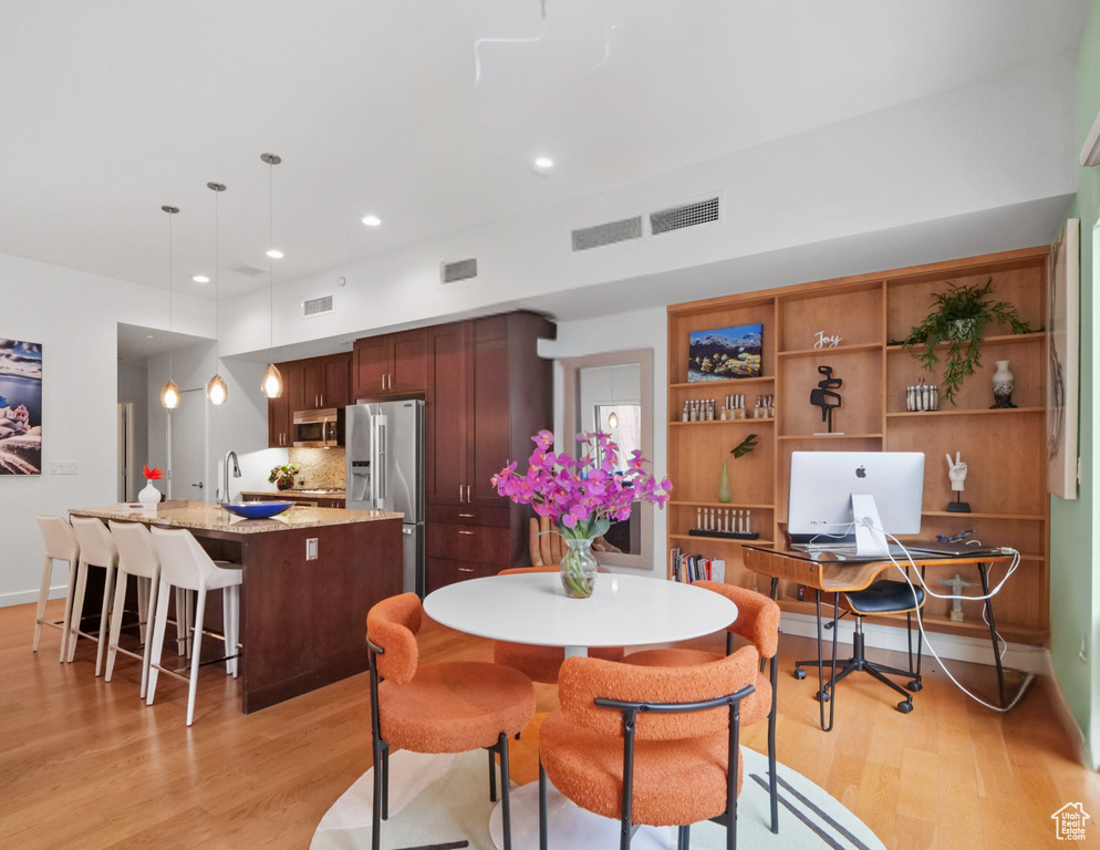 Dining area with light wood finished floors, an office area, and recessed lighting
