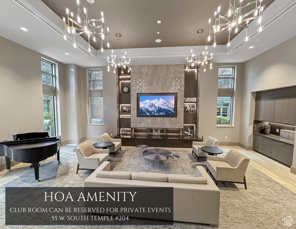 Living room with a chandelier, wood finished floors, recessed lighting, a high ceiling, and a raised ceiling