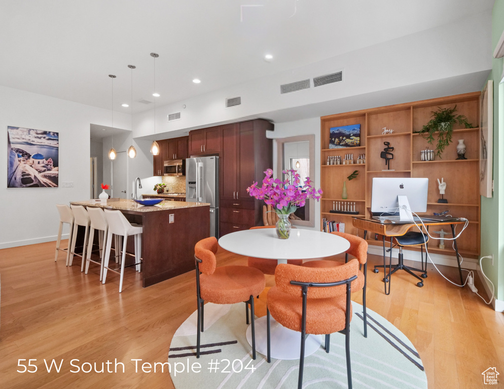 Dining room featuring light wood finished floors, an office area, and recessed lighting