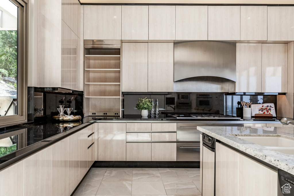 Kitchen featuring light stone countertops, wall chimney range hood, dishwasher, tasteful backsplash, and modern cabinets