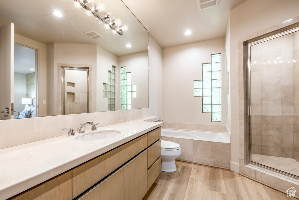 Ensuite bathroom with a garden tub, vanity, wood finished floors, a shower stall, and recessed lighting