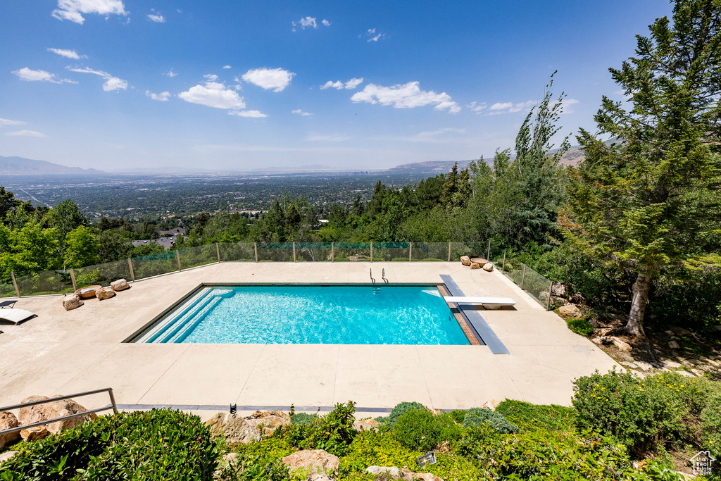 View of swimming pool with a patio area, a diving board, and a mountain view