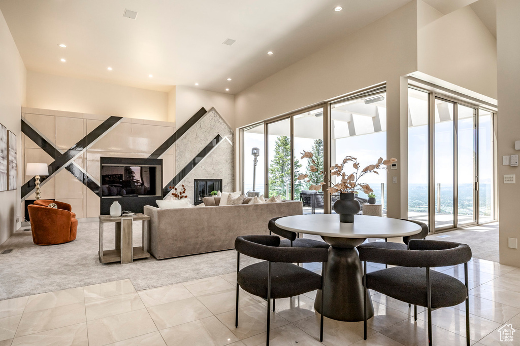 Dining area with light carpet, plenty of natural light, recessed lighting, light tile patterned floors, and a high ceiling