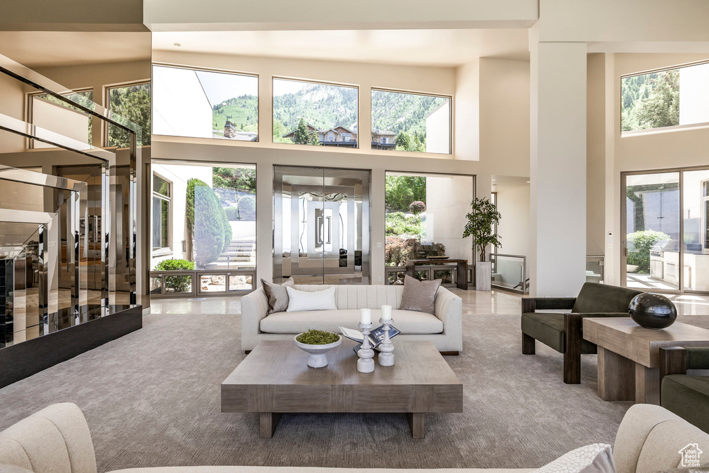 Living area featuring a towering ceiling, plenty of natural light, and stairs