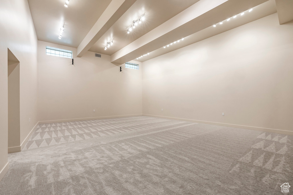 Unfurnished room with carpet floors and beam ceiling