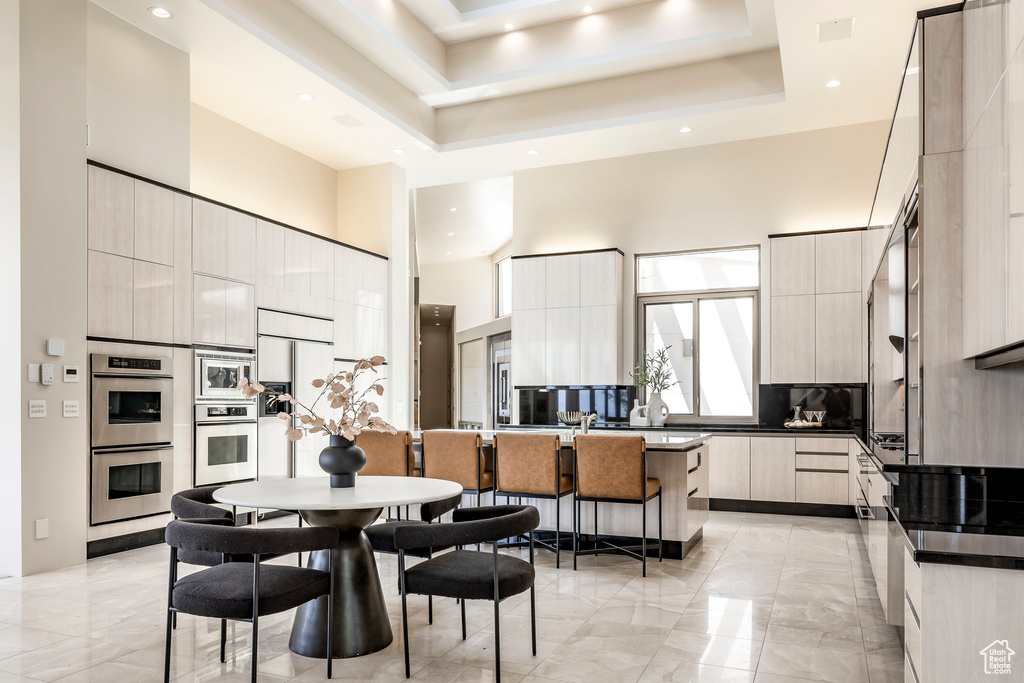 Kitchen featuring modern cabinets, built in appliances, a high ceiling, dark countertops, and decorative backsplash