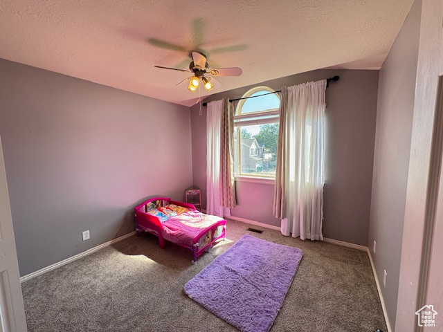 Carpeted bedroom with a textured ceiling and a ceiling fan