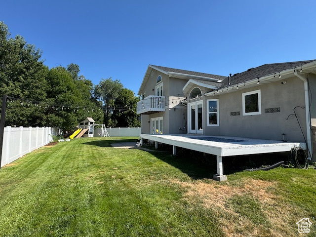 Rear view of property featuring a fenced backyard, french doors, stucco siding, and a wooden deck