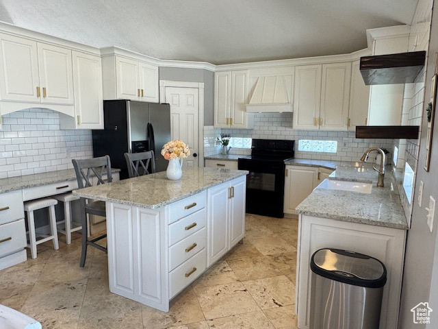 Kitchen featuring black range with electric cooktop, premium range hood, stainless steel fridge with ice dispenser, decorative backsplash, and a center island