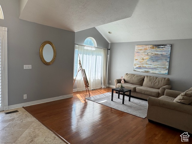 Living room featuring lofted ceiling, a textured ceiling, and wood finished floors