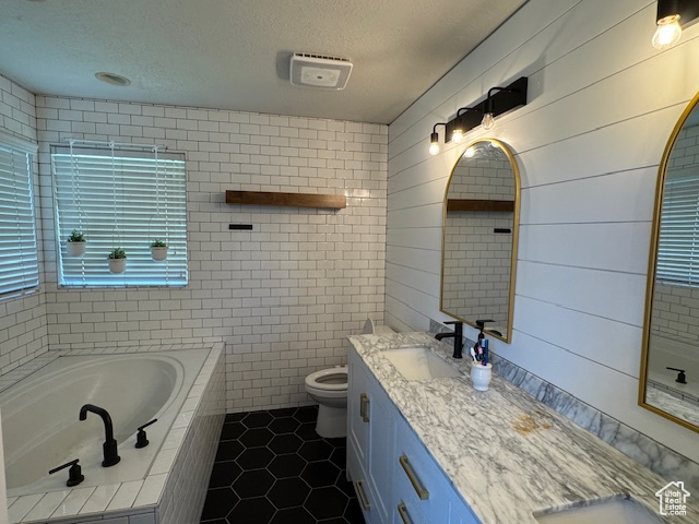Full bath featuring double vanity, a bath, tile patterned flooring, a textured ceiling, and tile walls