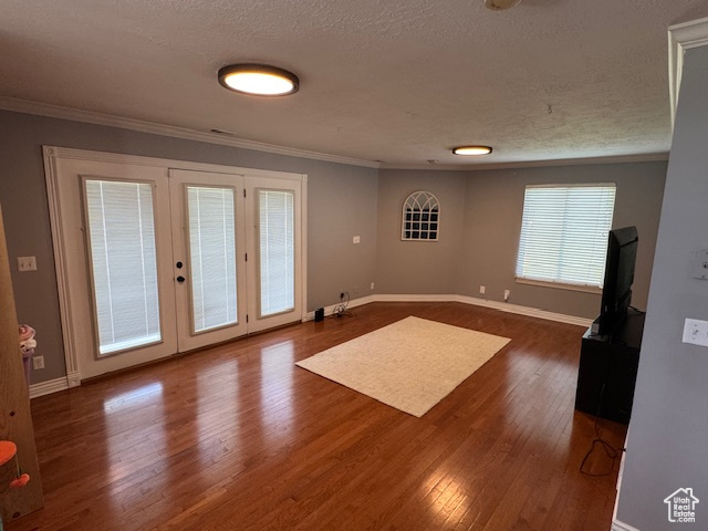 Spare room with ornamental molding, dark wood finished floors, french doors, and a textured ceiling