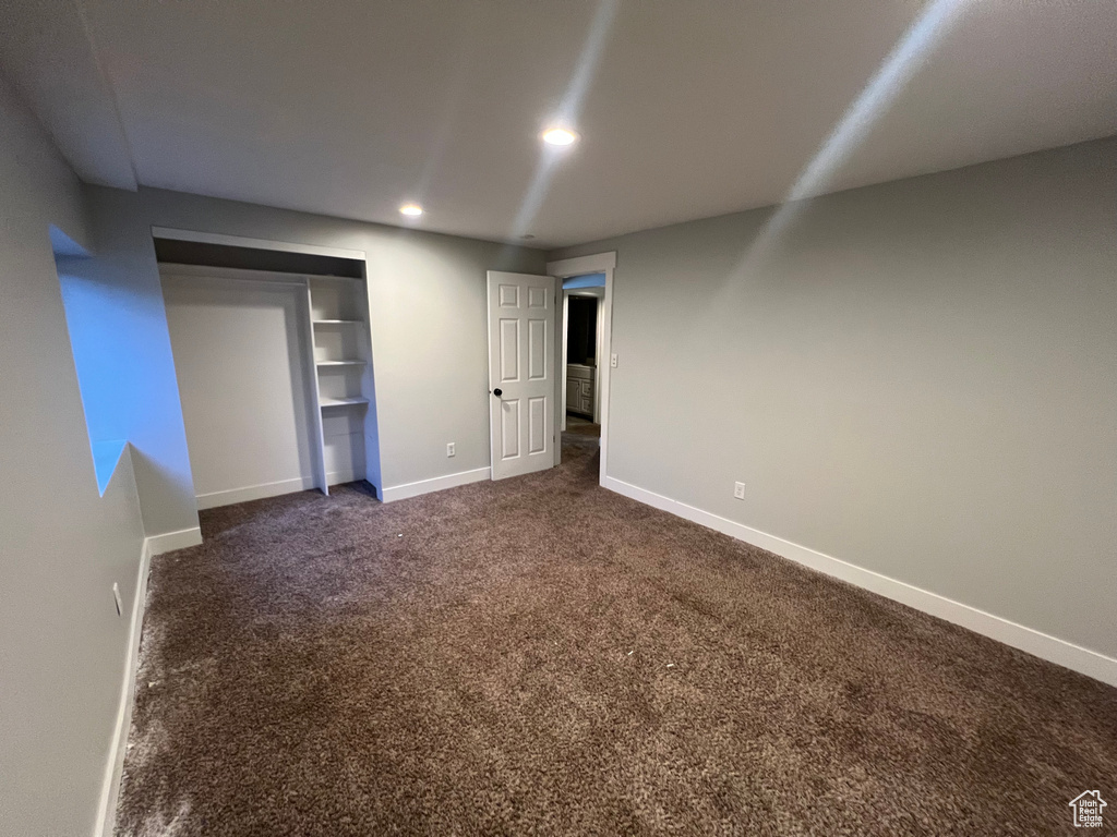 Unfurnished bedroom with dark colored carpet, recessed lighting, and a closet