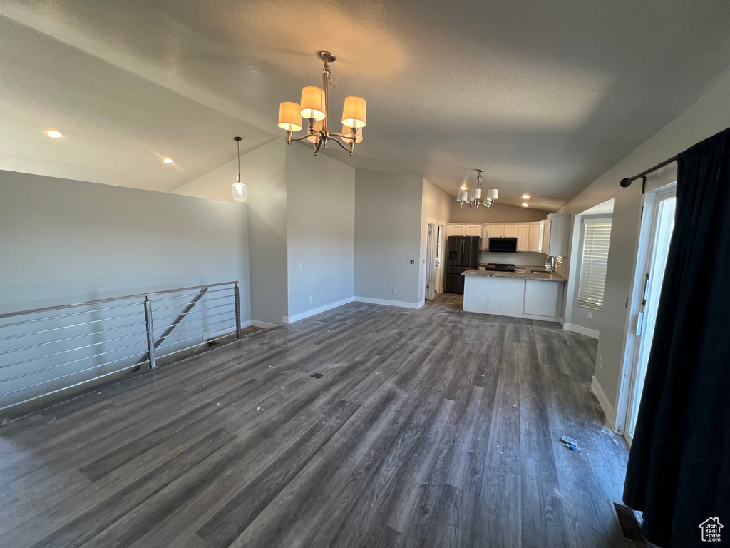 Unfurnished living room with a chandelier, vaulted ceiling, dark wood-style floors, and recessed lighting