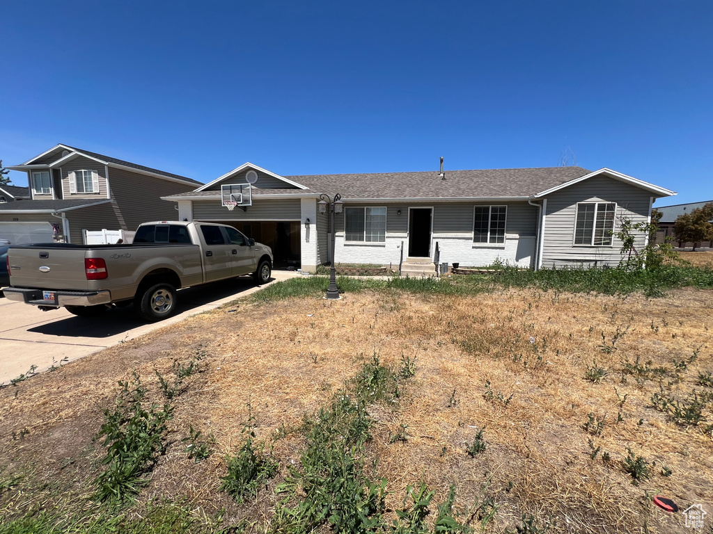 Single story home with an attached garage, concrete driveway, and a shingled roof