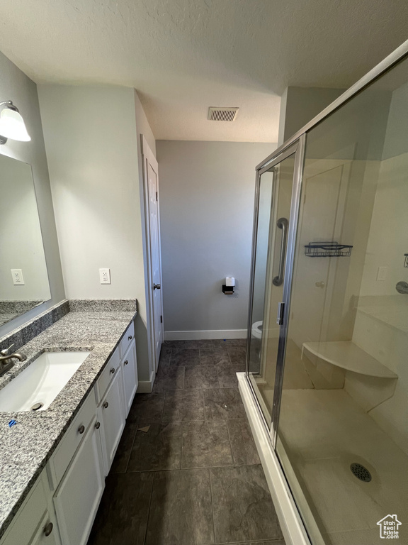 Bathroom featuring vanity, a stall shower, and a textured ceiling