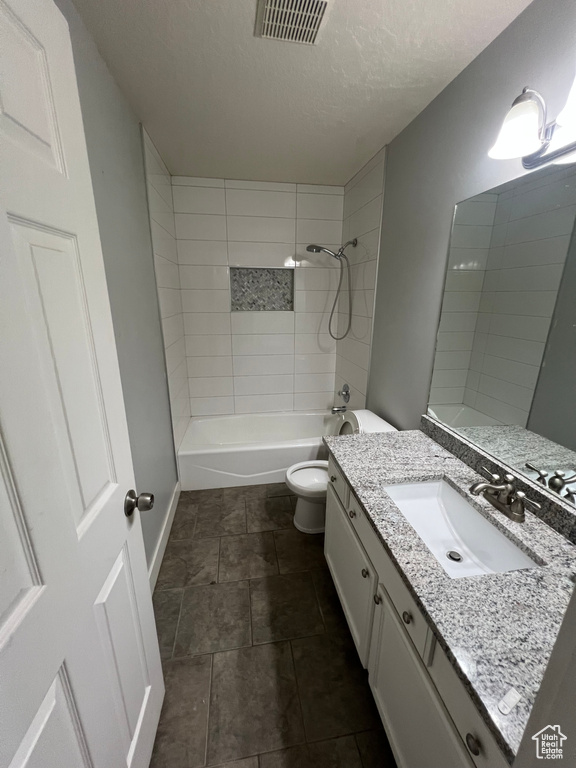 Bathroom with vanity, a textured ceiling, bathtub / shower combination, and tile patterned flooring