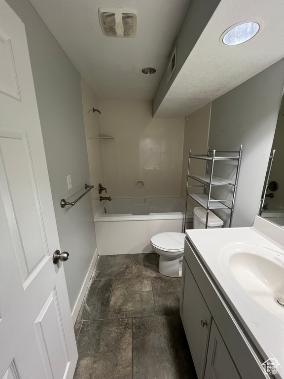 Bathroom featuring vanity, stone finish flooring, and  shower combination