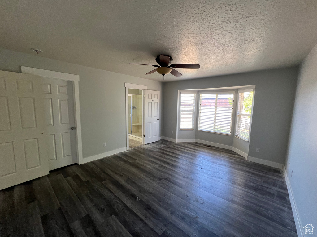Unfurnished bedroom featuring dark wood-type flooring, a textured ceiling, ceiling fan, and ensuite bath