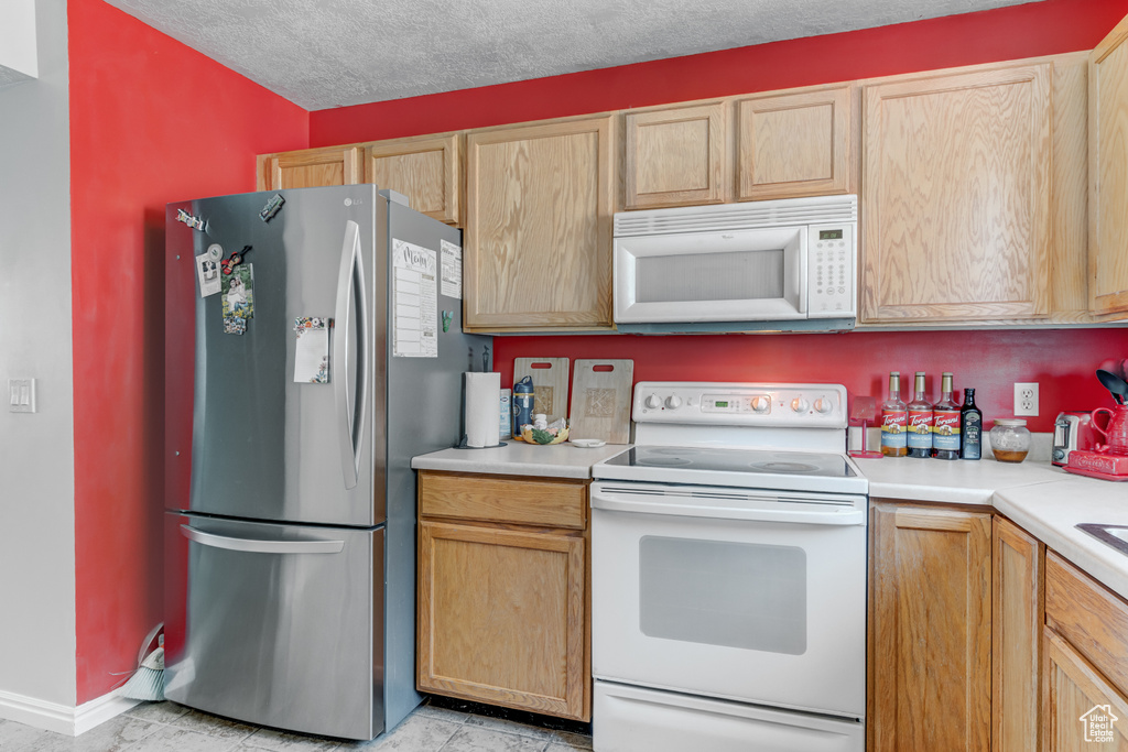 Kitchen featuring white appliances, light countertops, and light tile patterned flooring