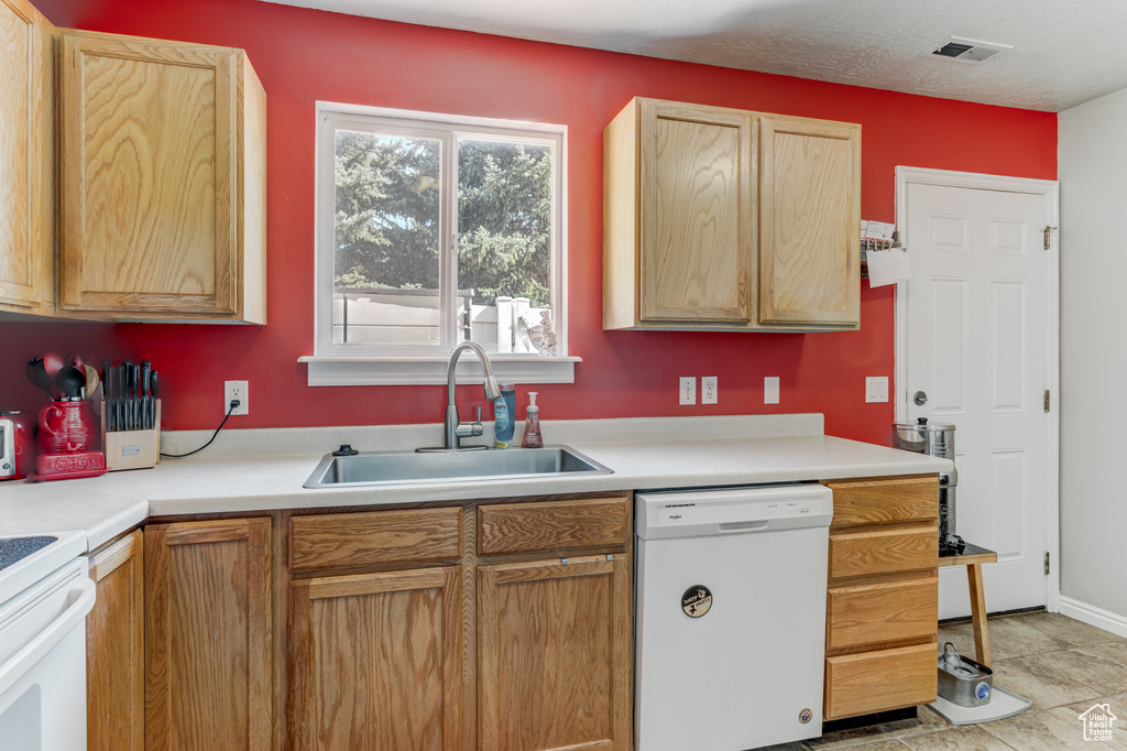 Kitchen with white dishwasher, light countertops, stove, and light tile patterned floors
