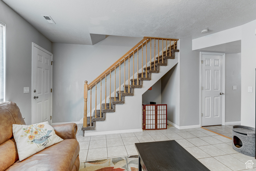 Tiled living room with stairway and baseboards