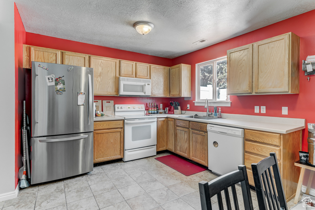 Kitchen with white appliances, light countertops, and a textured ceiling