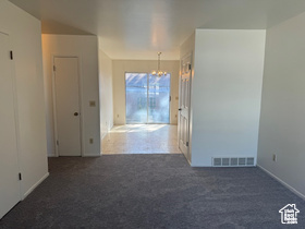 Spare room featuring carpet flooring and a chandelier