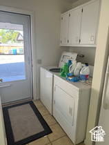 Laundry area featuring independent washer and dryer, plenty of natural light, light tile patterned flooring, and cabinet space