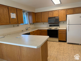 Kitchen featuring white appliances, brown cabinets, and a peninsula