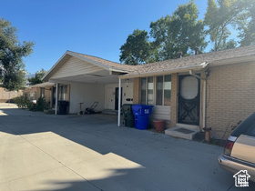 View of front of house featuring driveway, an attached carport, and brick siding