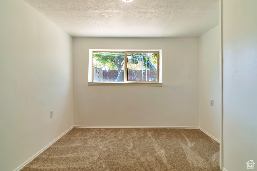 Carpeted empty room featuring a textured ceiling and baseboards