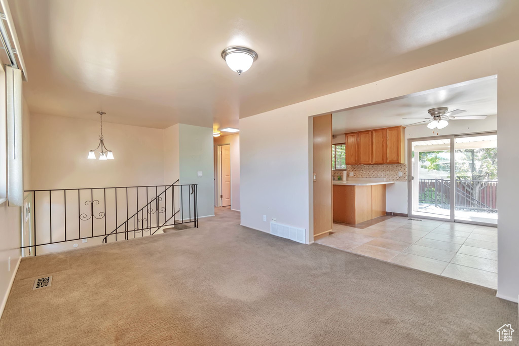Unfurnished living room with light colored carpet, ceiling fan, and light tile patterned floors