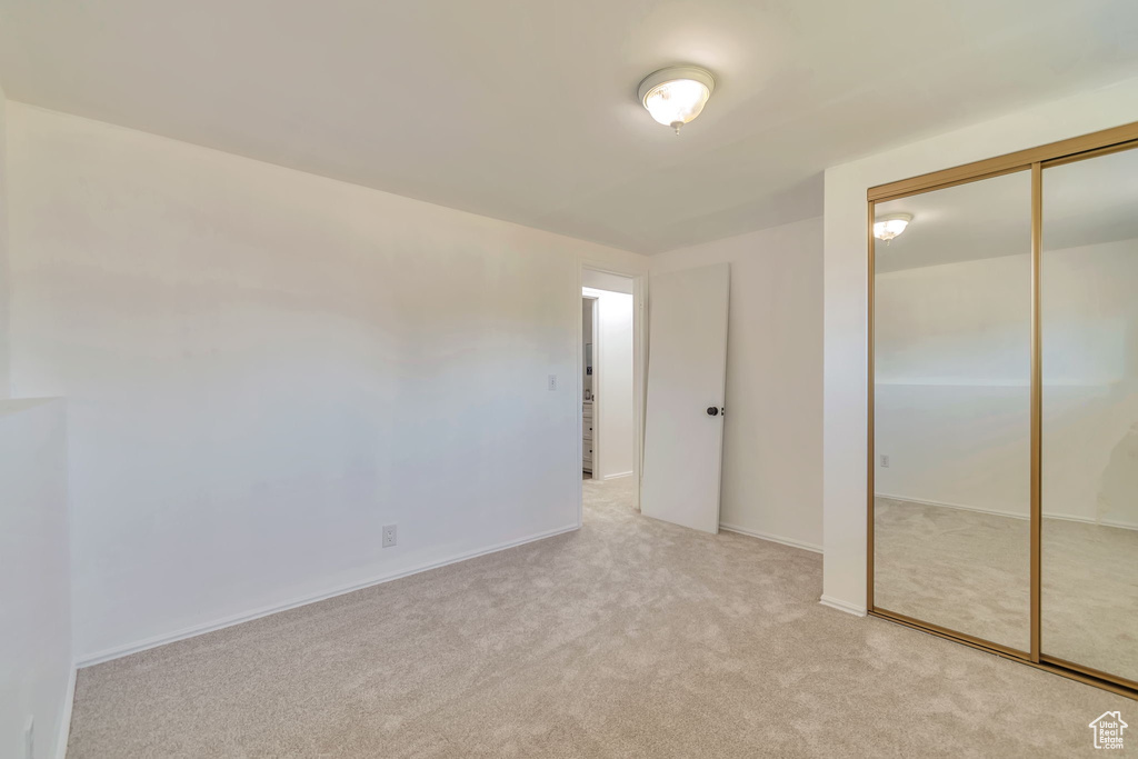 Unfurnished bedroom with light carpet and a closet