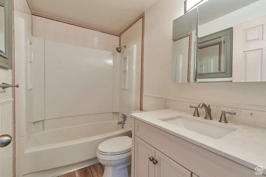 Bathroom featuring vanity,  shower combination, and wood finished floors