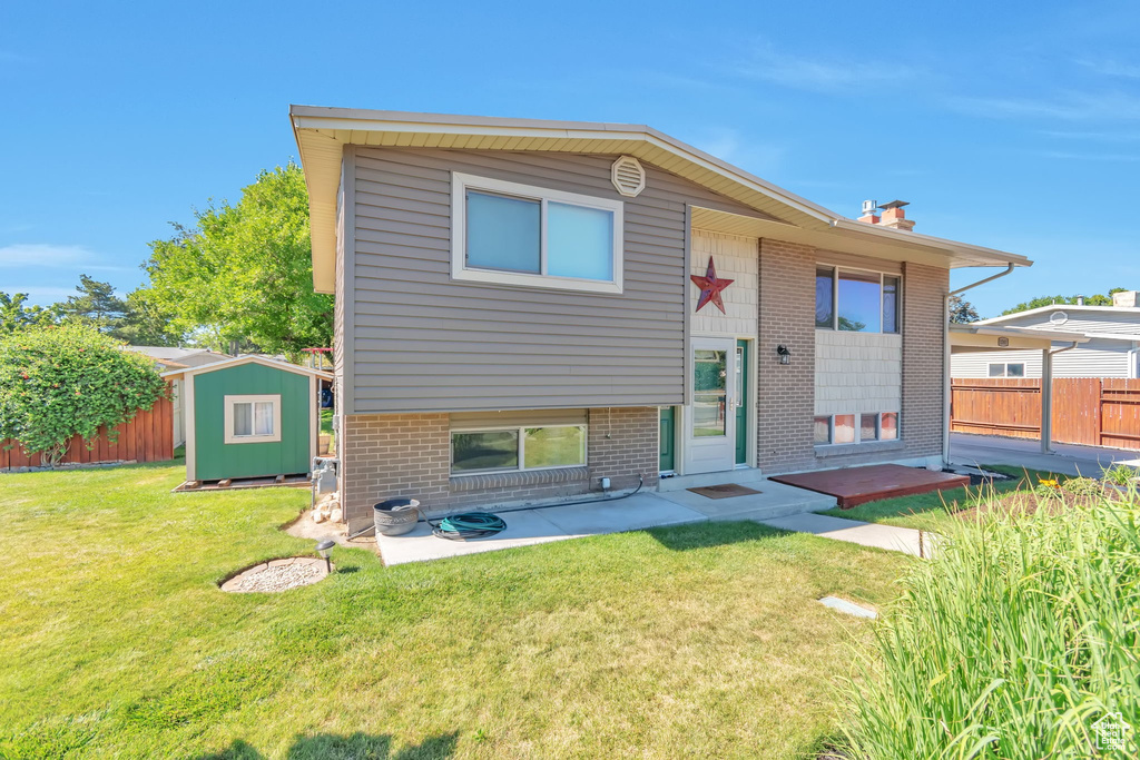Back of property featuring a storage shed, brick siding, a patio area, and a chimney