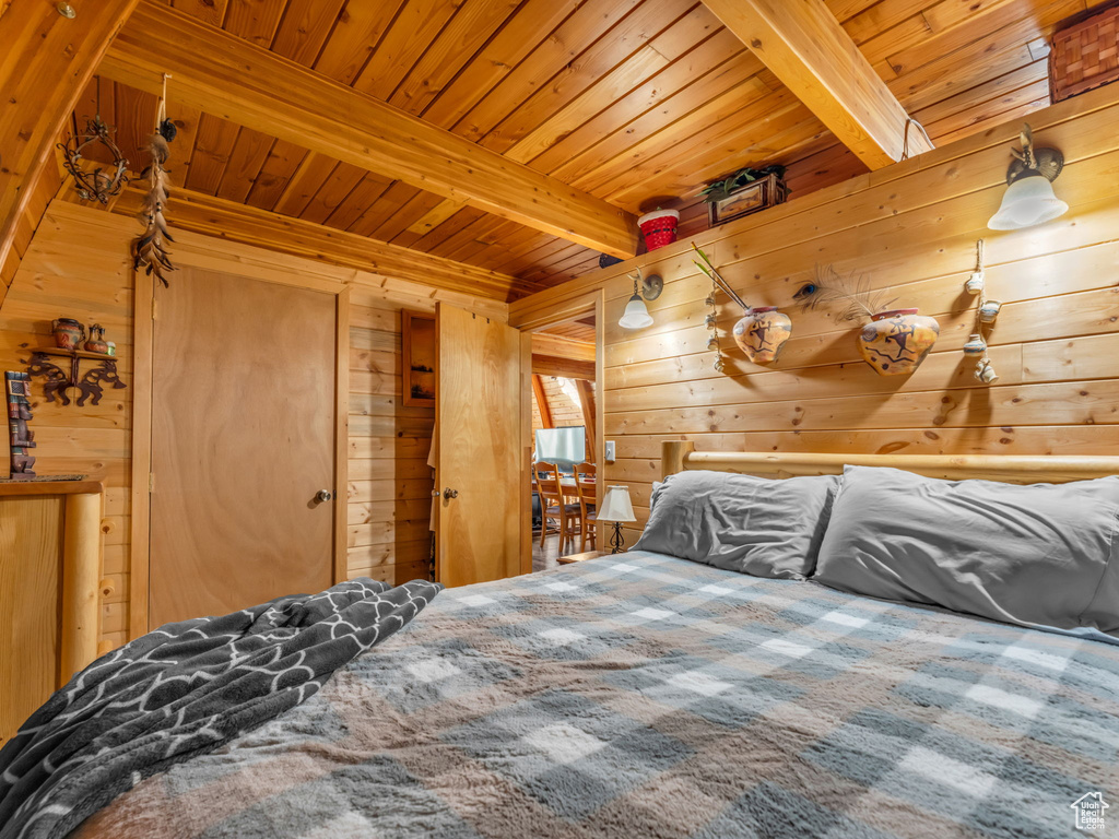 Bedroom featuring a wood ceiling with exposed beams and wood walls