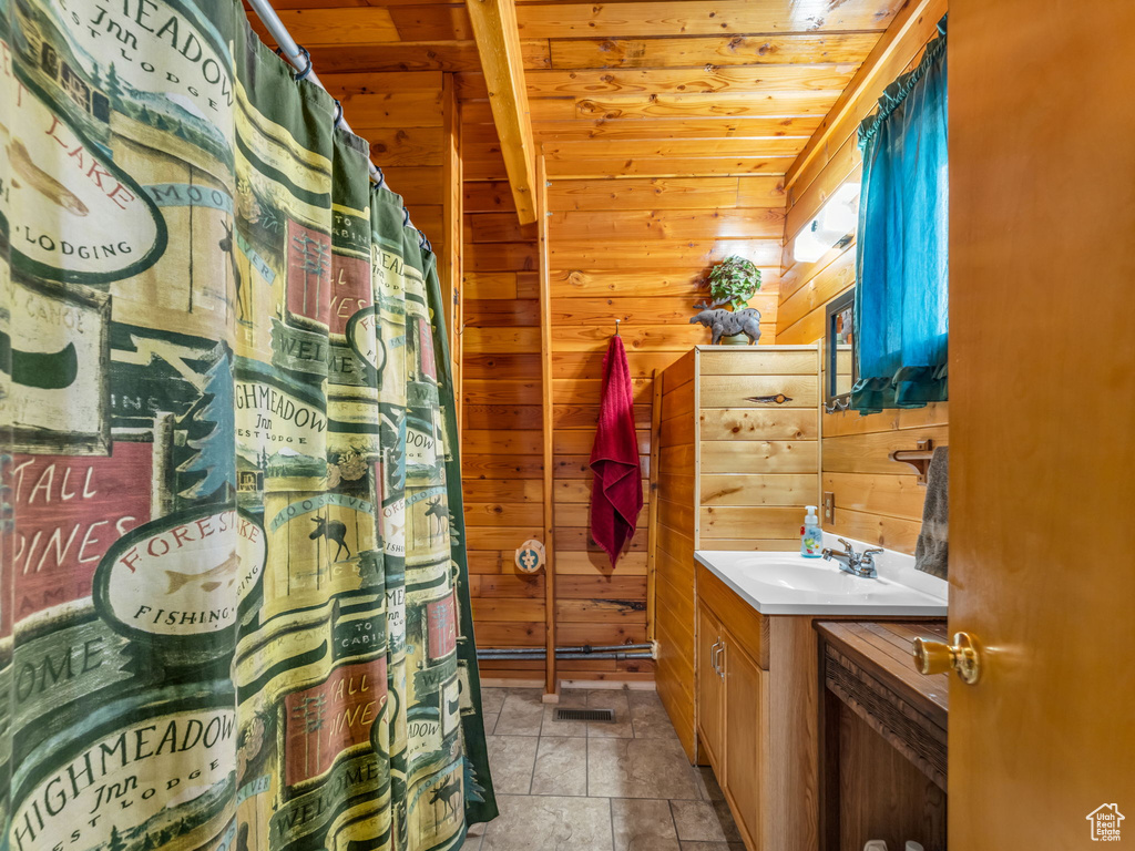 Bathroom with vanity, wood ceiling, wood walls, and a shower with shower curtain