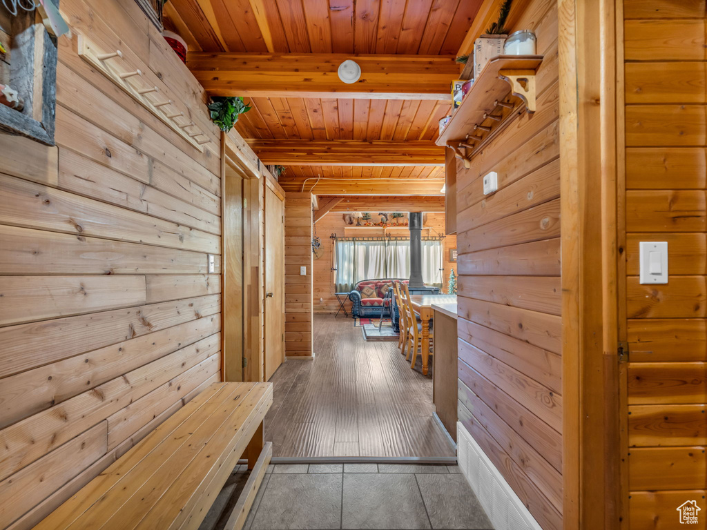 Hall featuring a wooden ceiling with exposed beams and wood walls